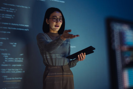 asian woman developer presentation about coding software data with devops team at night in officeの写真素材