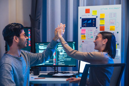 asian and Indian Developer team clapping hand for project success  with software computer at night in officeの写真素材