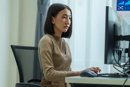 Asian prompt engineer develop coding app with software data sitting in front of computer monitor at officeの写真素材