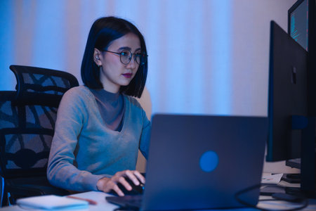 Asian woman  software development working on coding  computer screen and flowchart at night in modern officeの写真素材