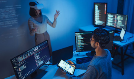 developer uses a VR headset to interact with projected interface designs, while colleagues discuss and code on screens, highlighting the integration of virtual reality and UI/UX design in modern software development.の写真素材