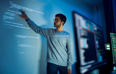 Indian man programmer standing in front of a screen with code projected  presentation the integration of technology and human expertise in software developmentの写真素材