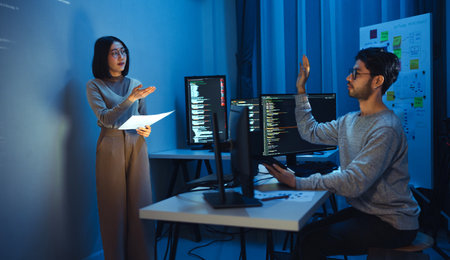 trainee developer hand up to ask speaker about software coding project presentation at night in officeの写真素材