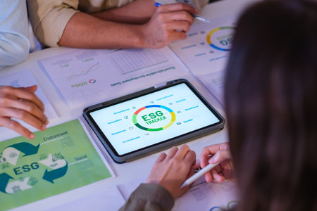 close up diversity team brainstorming focused on ESG (environment,social,governance)  with tablet or sdgs goals in a sustainable green office at nightの写真素材