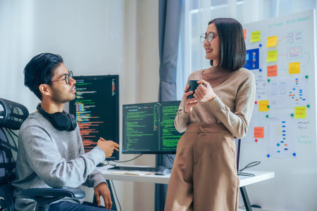Two software developers engage in a discussion at coffee break time in a modern office, relax...