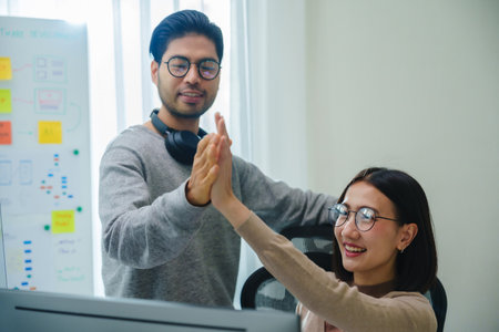 asian and Indian Developer team clapping hand for project success  with software computer at officeの写真素材