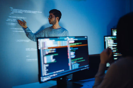 Indian man programmer standing in front of a screen with code projected  presentation the...