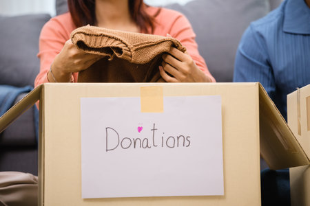 group of friend  sorting and packing clothes into a donation box.community support, and charitable givingの写真素材