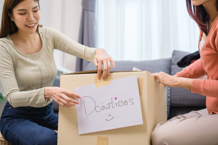 group of friend  sorting and packing clothes into a donation box.community support, and charitable...