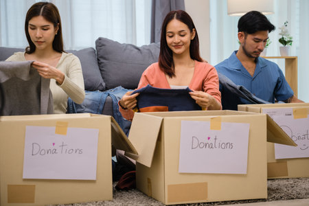 group of friend  sorting and packing clothes into a donation box.community support, and charitable givingの写真素材