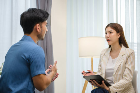 asian man engaged in a one-on-one therapy session with a professional counselor in a calm and supportive environmentの写真素材