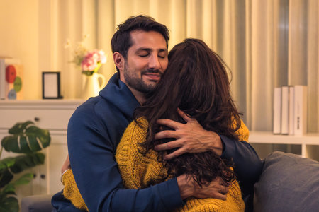 Loving couple hugging romantically together at home, happy in their relationship with deep affection and heartfelt reconciliationの写真素材
