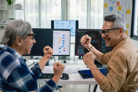 Senior developer team celebrates success in software collaboration and coding at a modern computer workstationの写真素材
