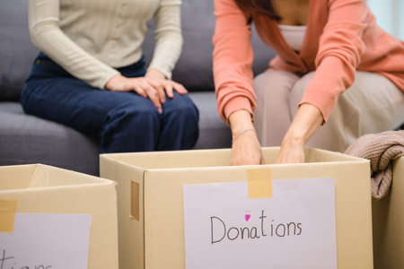 group of friend  sorting and packing clothes into a donation box.community support, and charitable givingの写真素材
