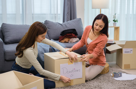 group of friend  sorting and packing clothes into a donation box.community support, and charitable givingの写真素材