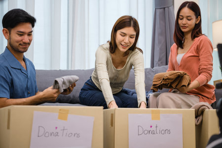 group of friend  sorting and packing clothes into a donation box.community support, and charitable givingの写真素材