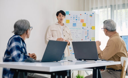 senior programmer bootcamlp,Asian young instructor guides senior learners through a programming on whiteboard, highlighting algorithm thinking and simple code exercisesの写真素材