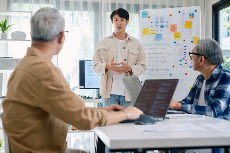 senior programmer bootcamlp,Asian young instructor guides senior learners through a programming on whiteboard, highlighting algorithm thinking and simple code exercisesの写真素材