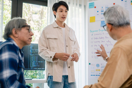 senior programmer bootcamlp,Asian young instructor guides senior learners through a programming on whiteboard, highlighting algorithm thinking and simple code exercisesの写真素材