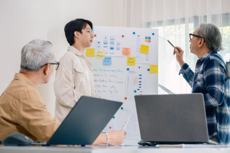 senior programmer bootcamlp,Asian young instructor guides senior learners through a programming on whiteboard, highlighting algorithm thinking and simple code exercisesの写真素材