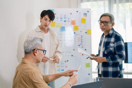 senior programmer bootcamlp,Asian young instructor guides senior learners through a programming on whiteboard, highlighting algorithm thinking and simple code exercisesの写真素材