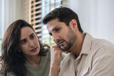 Supportive couple in emotional moment at home as woman struggles with sadness and stress, expressingの写真素材