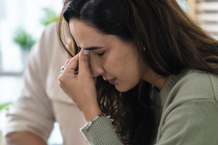 Supportive couple in emotional moment at home as woman struggles with sadness and stress, expressingの写真素材