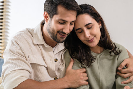 Supportive couple in emotional moment at home as woman struggles with sadness and stress, expressingの写真素材