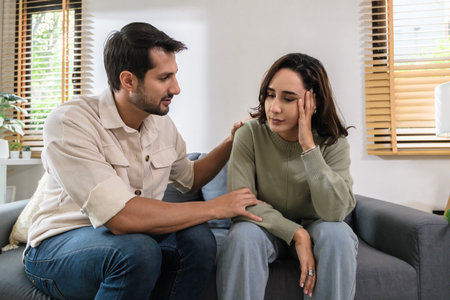 Supportive couple in emotional moment at home as woman struggles with sadness and stress, expressingの写真素材