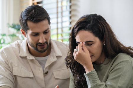 Supportive couple in emotional moment at home as woman struggles with sadness and stress, expressingの写真素材