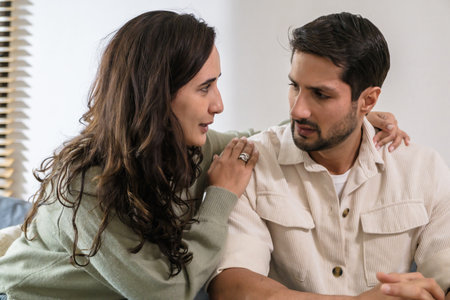 Supportive couple in emotional moment at home as woman struggles with sadness and stress, expressingの写真素材