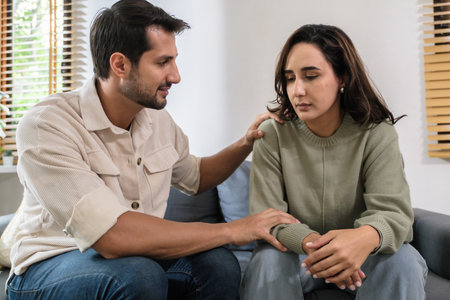 Supportive couple in emotional moment at home as woman struggles with sadness and stress, expressingの写真素材