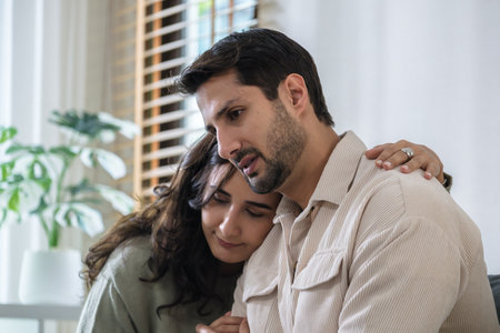 Supportive couple in emotional moment at home as woman struggles with sadness and stress, expressingの写真素材