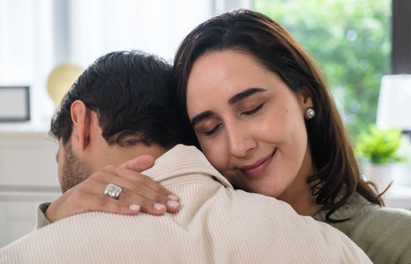 Supportive couple in emotional moment at home as woman struggles with sadness and stress, expressingの写真素材