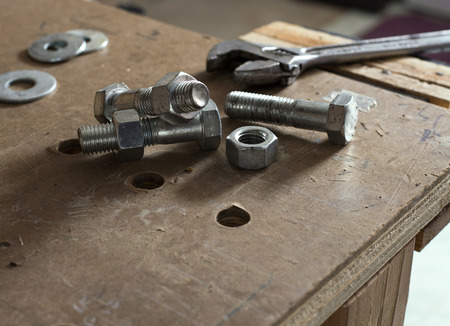 Nuts and bolts on workbench with wrench in background