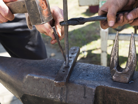 Blacksmith forge with hammer iron on anvil. Detail of working hands. Daily sunshineの写真素材