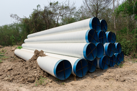 Close up large concrete pipe under loamy sand mounds to the rural dirt road.の写真素材