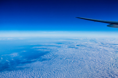 View from plane over the wing to clouds and ocean underneathの写真素材