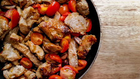 Portion barbecue pork steak tomatoes in frying pan close upの写真素材