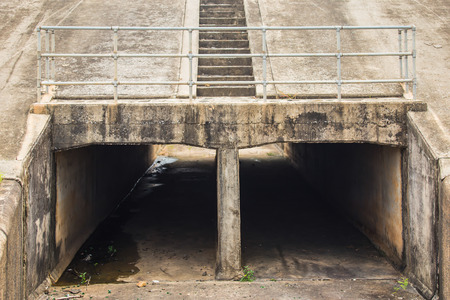 View through a concrete drainage pipe culvert under a desert roadの写真素材