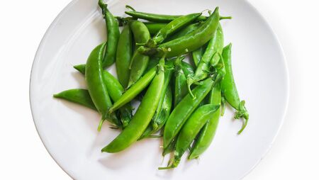 Green peas in a plate on white backgroundの写真素材