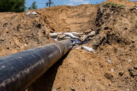 Close up large concrete pipe under loamy sand mounds to the rural dirt road