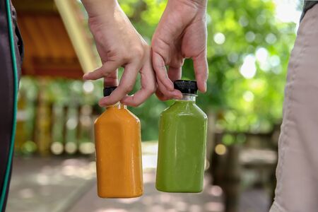 Woman who holds a bottle of orange milk tea and green tea by handの写真素材