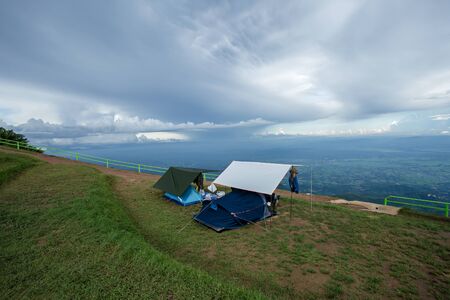 Camping tent in campground at national park. Tourists camped in the woods on the shore of the lake on the hillside. View of tent on meadow in forest. Camping backgroundの写真素材