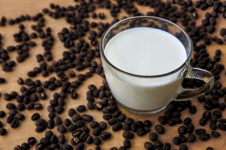 Fresh milk in a glass, placed on a wooden floor with coffee beansの写真素材