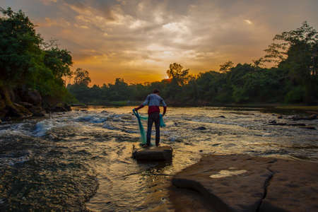 Men carrying nets for catching fish in Thai countryside at sunsetの写真素材