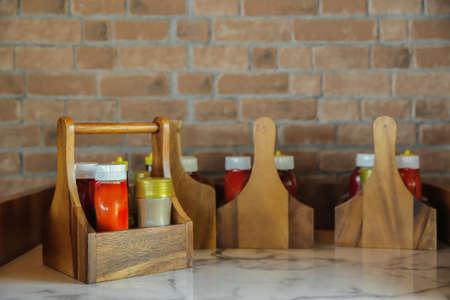 Breakfast condiments sets, such as chili sauce, pepper bottles in a wooden box on the tableの写真素材