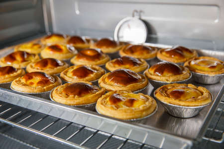 Pasteis de Nata or Belem Tart. Portuguese Custard made with Egg, Cinnamon, Sugar and Flour in Muffin Tray / Cupcake Mol in Oven. Traditional Dessertの写真素材