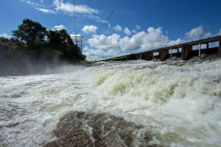 Reservoir Dam Spillway with Water Pouring over the Top in the Mountainsの写真素材