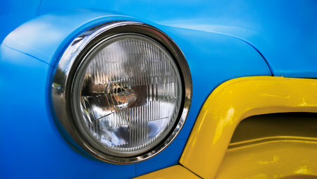 Headlight of a blue vintage car on the background of a yellow car
